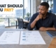 A Botswana entrepreneur at a wooden office desk thoughtfully evaluating two marketing project proposals.