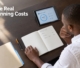 A business owner reviewing recurring website expenses, hosting, and domain budgets on a workspace tablet and ledger.